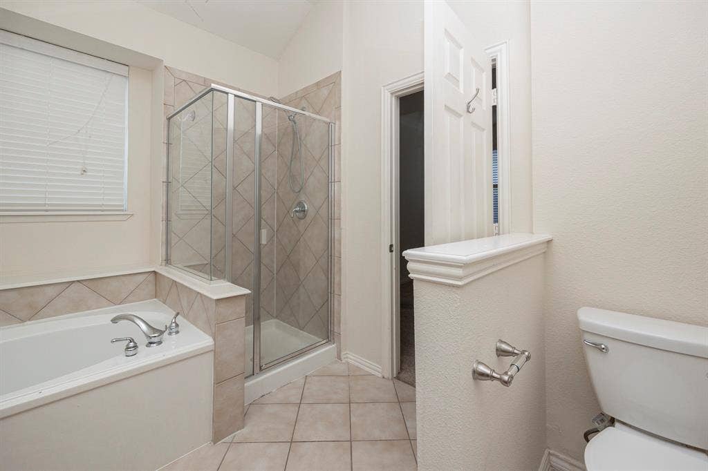 5728 Calloway Drive, McKinney, TX 75070 Built-in tub with chrome fixtures, glass-enclosed shower with tile surround, and tile flooring
