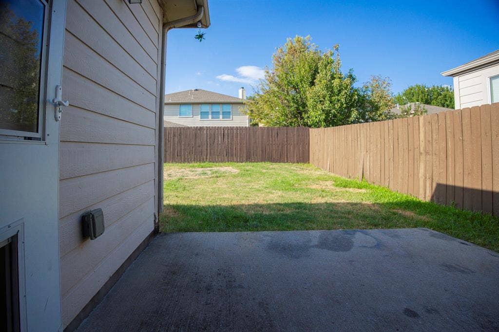 5728 Calloway Drive, McKinney, TX 75070 Expansive fenced yard featuring a concrete patio, wood privacy fence, and mature trees