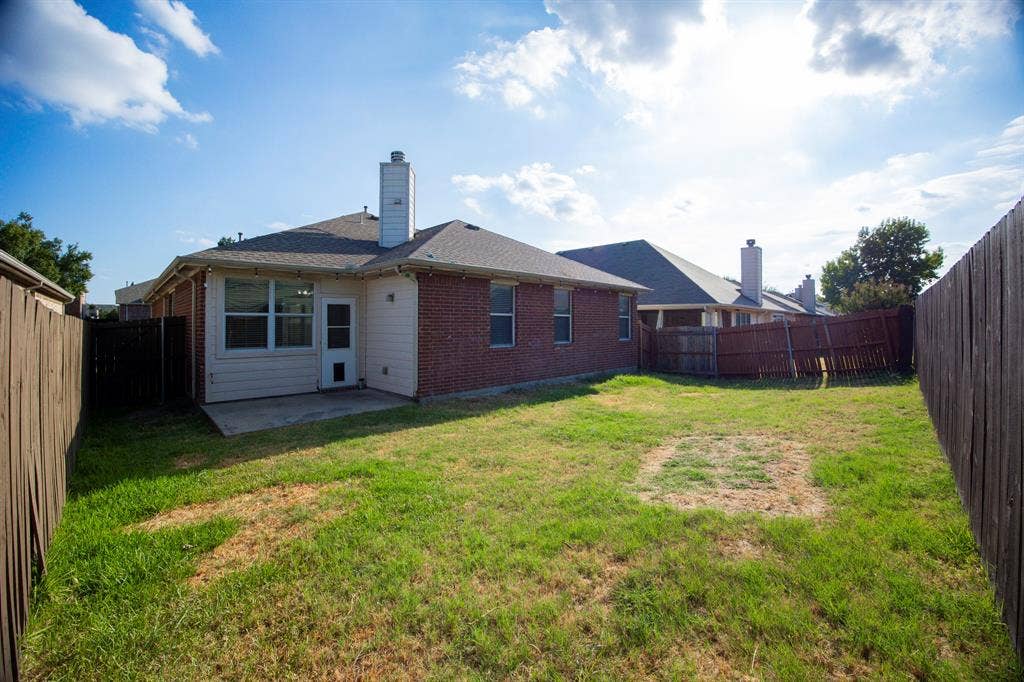 5728 Calloway Drive, McKinney, TX 75070 Brick exterior with a white chimney, concrete patio, and fenced backyard