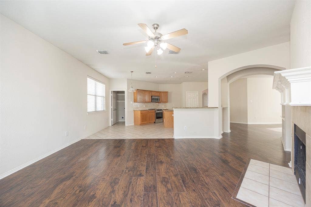 5728 Calloway Drive, McKinney, TX 75070 Spacious room featuring wood-finish flooring, a ceiling fan, and a fireplace with a white mantel