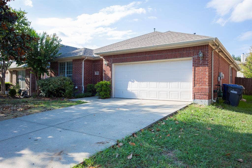5728 Calloway Drive, McKinney, TX 75070 Brick exterior with a paneled garage door and a concrete driveway