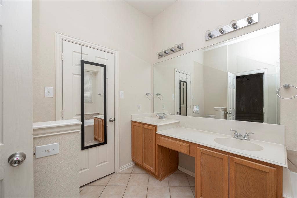 5728 Calloway Drive, McKinney, TX 75070 Dual vanity with light wood-finish cabinetry, integrated sinks, and chrome fixtures