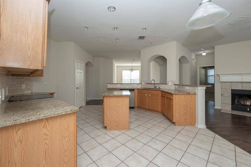 5728 Calloway Drive, McKinney, TX 75070 Kitchen featuring an integrated cooktop, granite countertops, wood cabinetry, stainless steel dishwasher, and recessed lighting