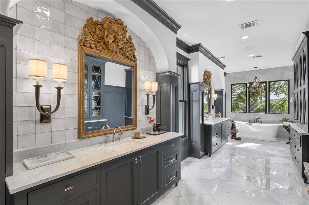 5 SAVANNAH Circle, Frisco, TX 75034 Spa-inspired primary bath pairs custom cabinetry, marble surfaces and sophisticated architectural detailing.