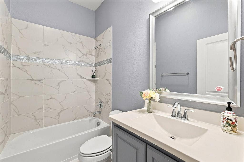 Bathtub with tiled surround featuring a decorative mosaic accent band