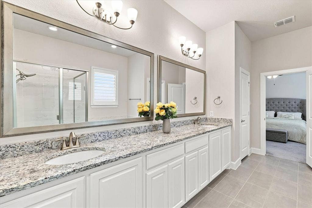 Dual vanity with white cabinetry and light-toned countertops, set on large format tile flooring