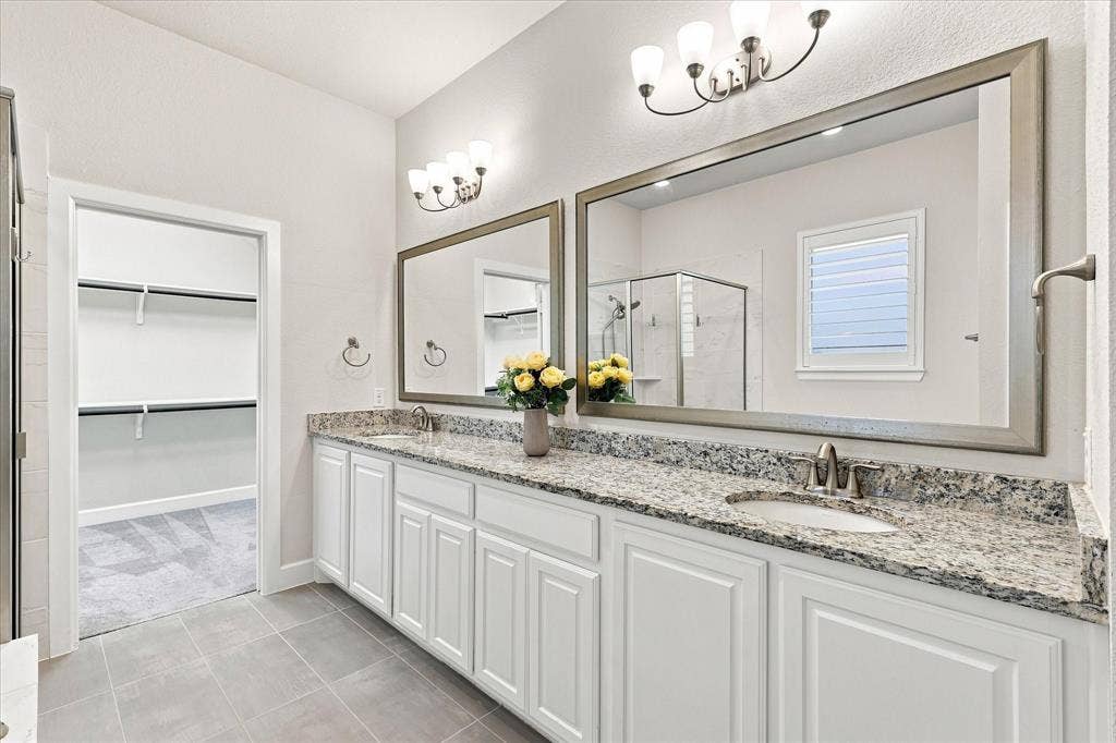 Dual vanity with granite countertops, undermount sinks, and white cabinetry