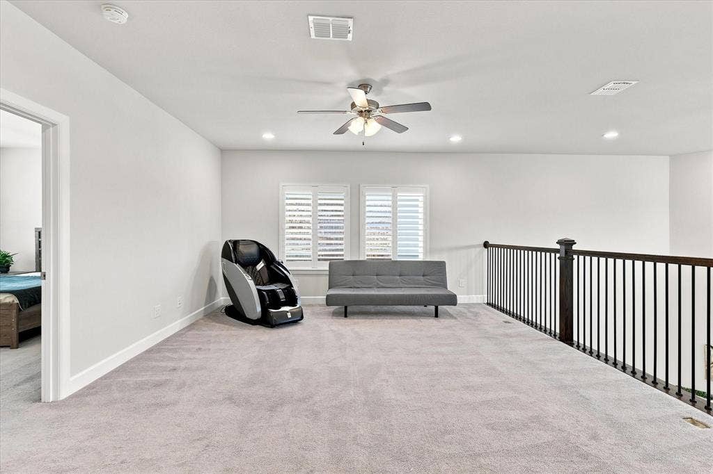 Spacious carpeted area with white walls, recessed lighting, and a ceiling fan