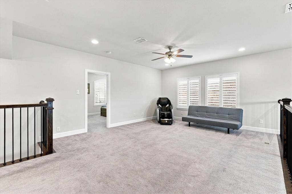 Spacious room with light gray carpeting, recessed lighting, ceiling fan, and plantation shutters