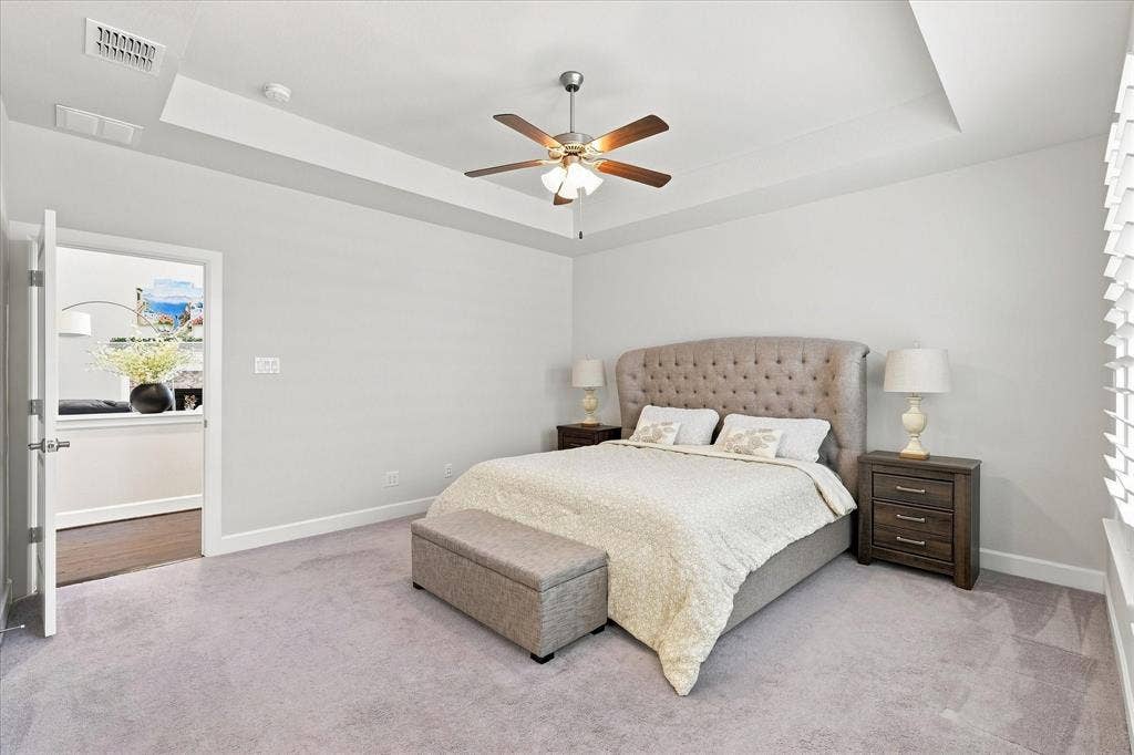 Tray ceiling with a ceiling fan, carpeted flooring, and white interior walls