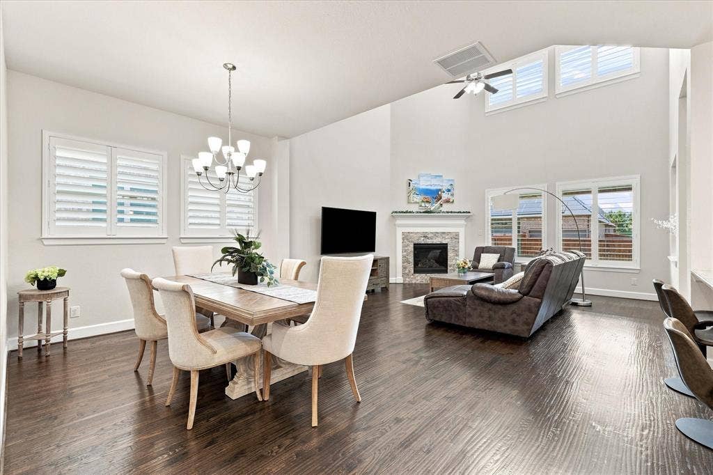 Hardwood-finish flooring throughout, a vaulted ceiling with integrated ceiling fan, and a fireplace with a stone surround