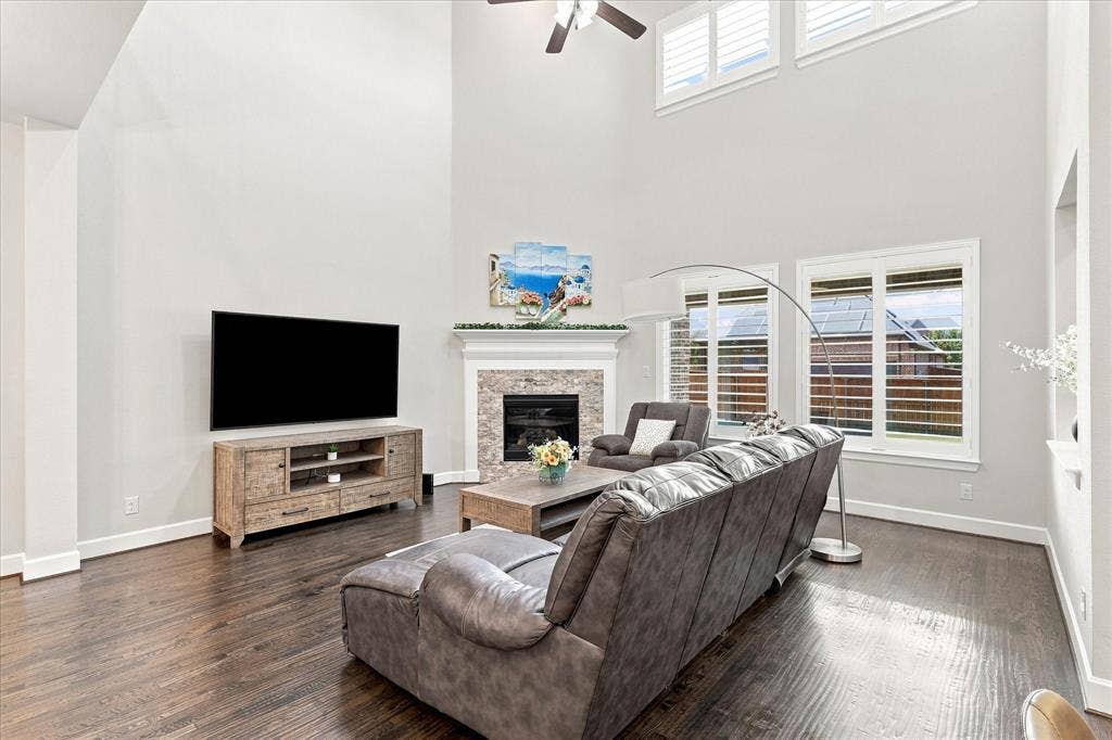 Vaulted ceilings, dark wood-finish flooring, and a stone-surround fireplace with mantel