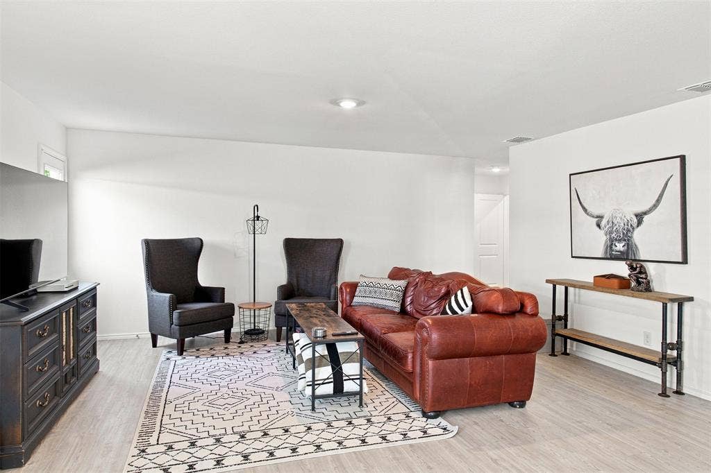 3409 Flicker Lane, McKinney, TX 75071 Recessed lighting illuminates the open living space, featuring light wood-finish flooring