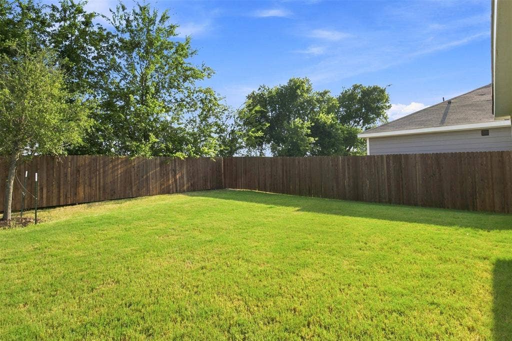 3409 Flicker Lane, McKinney, TX 75071 Expansive green lawn with a wood privacy fence