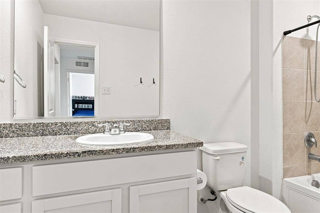 3409 Flicker Lane, McKinney, TX 75071 White vanity with shaker-style cabinetry, granite-finish countertop, and undermount sink