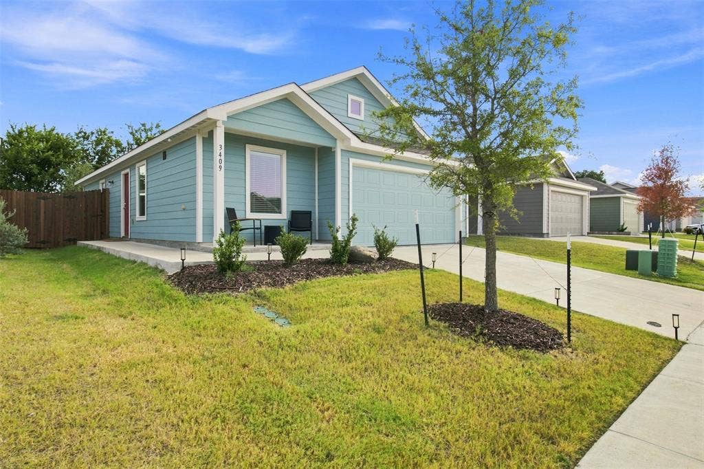 3409 Flicker Lane, McKinney, TX 75071 Single-story residence featuring light blue siding, an attached garage, a concrete driveway, and a fenced side yard