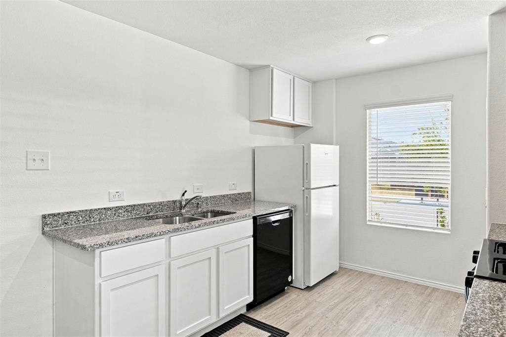 3409 Flicker Lane, McKinney, TX 75071 Kitchen featuring white cabinetry, speckled countertops, double basin sink, and wood-finish flooring