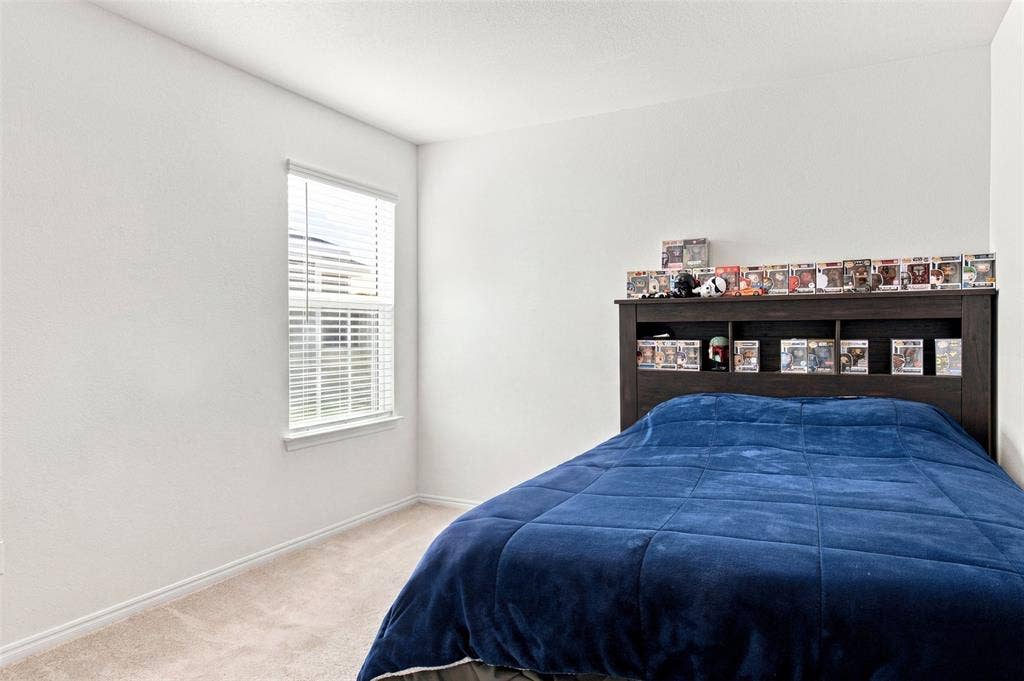 3409 Flicker Lane, McKinney, TX 75071 Built-in wood-finish headboard with integrated shelving, single window with blinds, and neutral carpeting