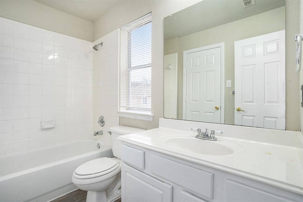 Full bathroom featuring a healthy amount of sunlight, vanity, toilet, and tiled shower / bath combo