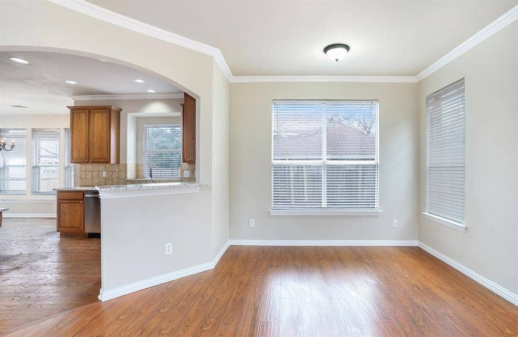 Kitchen with ornamental molding, dishwasher, hardwood / wood-style flooring, and backsplash