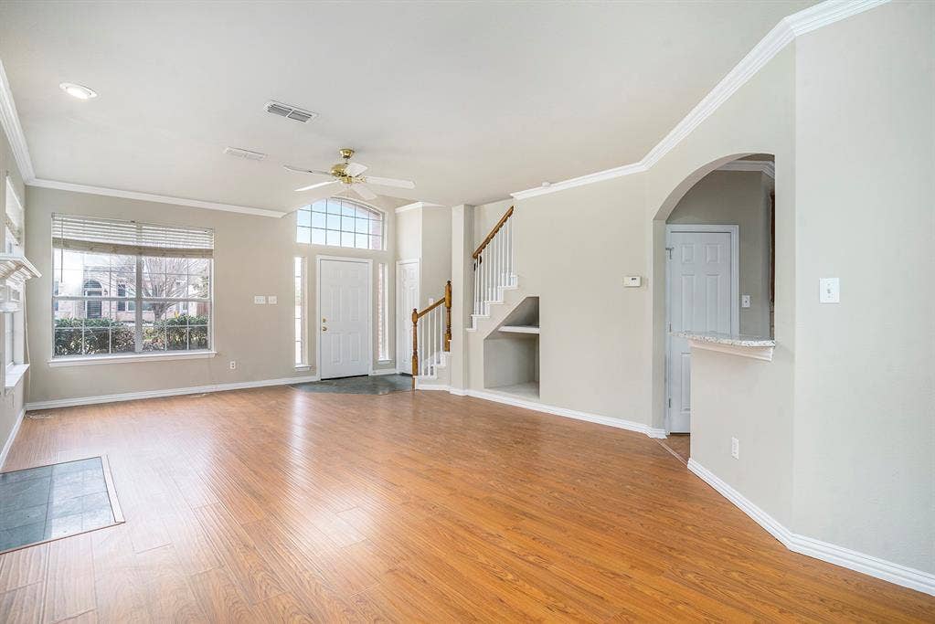 Unfurnished living room featuring crown molding, ceiling fan, and hardwood / wood-style floors
