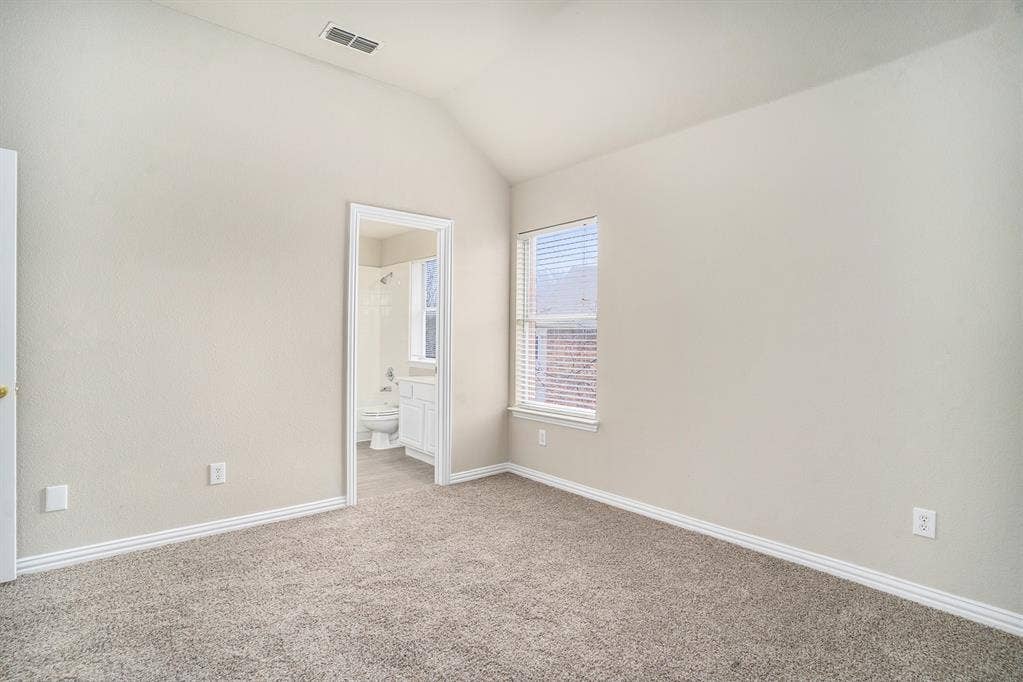 Empty room with carpet floors and lofted ceiling