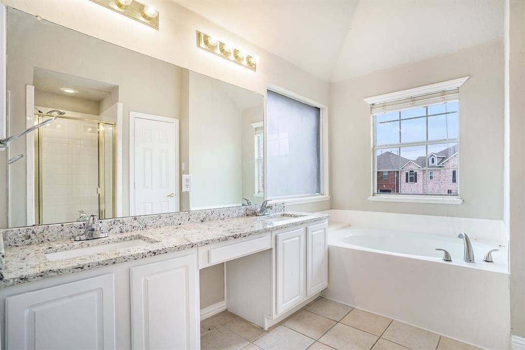 Bathroom featuring tile floors, vaulted ceiling, double vanity, and plus walk in shower