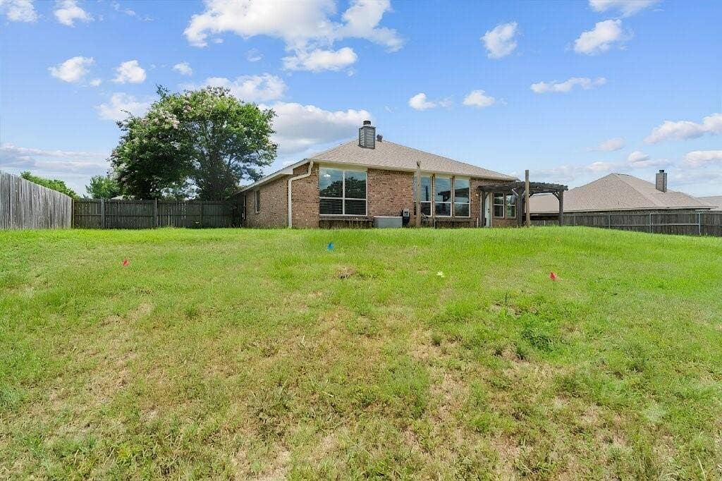 833 Greenwood Circle, Lindale, TX 75771 Expansive green space with a brick exterior, large windows, and a wooden pergola structure