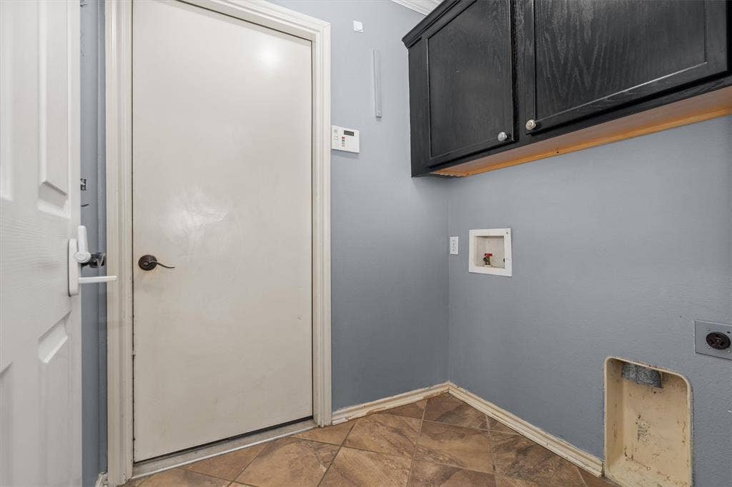 833 Greenwood Circle, Lindale, TX 75771 Utility room featuring blue-gray painted walls, dark cabinetry with wood-finish trim, wood-finish flooring, and direct entry door with hardware