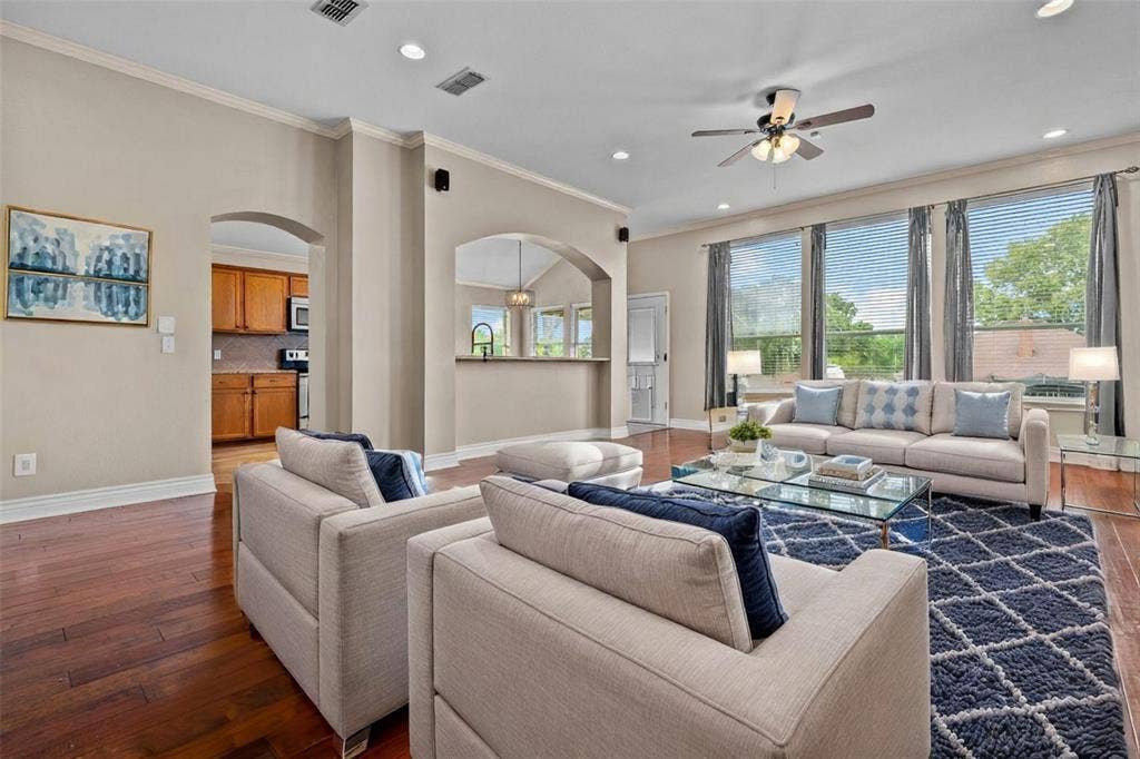 833 Greenwood Circle, Lindale, TX 75771 Spacious open-concept living area featuring hardwood flooring, multiple large windows with natural light, architectural columns, ceiling fan with recessed lighting, neutral wall finishes, and a gas fireplace with decorative surround