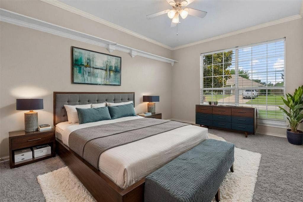 833 Greenwood Circle, Lindale, TX 75771 Master bedroom showcasing a wood-finish platform bed frame, dual nightstands with integrated storage, layered bedding in neutral tones, recessed ceiling with ceiling fan, and expansive sliding glass doors with plantation shutters opening to outdoor views