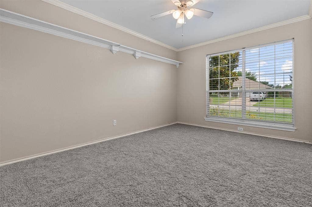 833 Greenwood Circle, Lindale, TX 75771 Spacious room showcasing neutral wall finishes, plush carpeting, abundant natural light from large windows with plantation shutters, ceiling fan with integrated lighting, and track lighting along the ceiling for flexible illumination