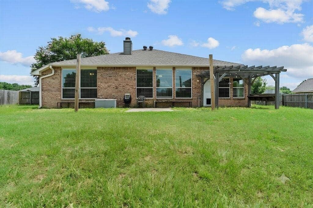 833 Greenwood Circle, Lindale, TX 75771 Brick exterior with multiple windows, a rear patio, and a wood pergola structure