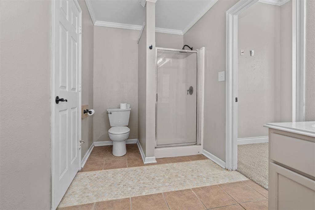 833 Greenwood Circle, Lindale, TX 75771 Spacious primary bathroom featuring a walk-in shower with glass enclosure and chrome hardware, dual-sink vanity with ample storage, ceramic tile flooring, and abundant natural lighting from multiple windows