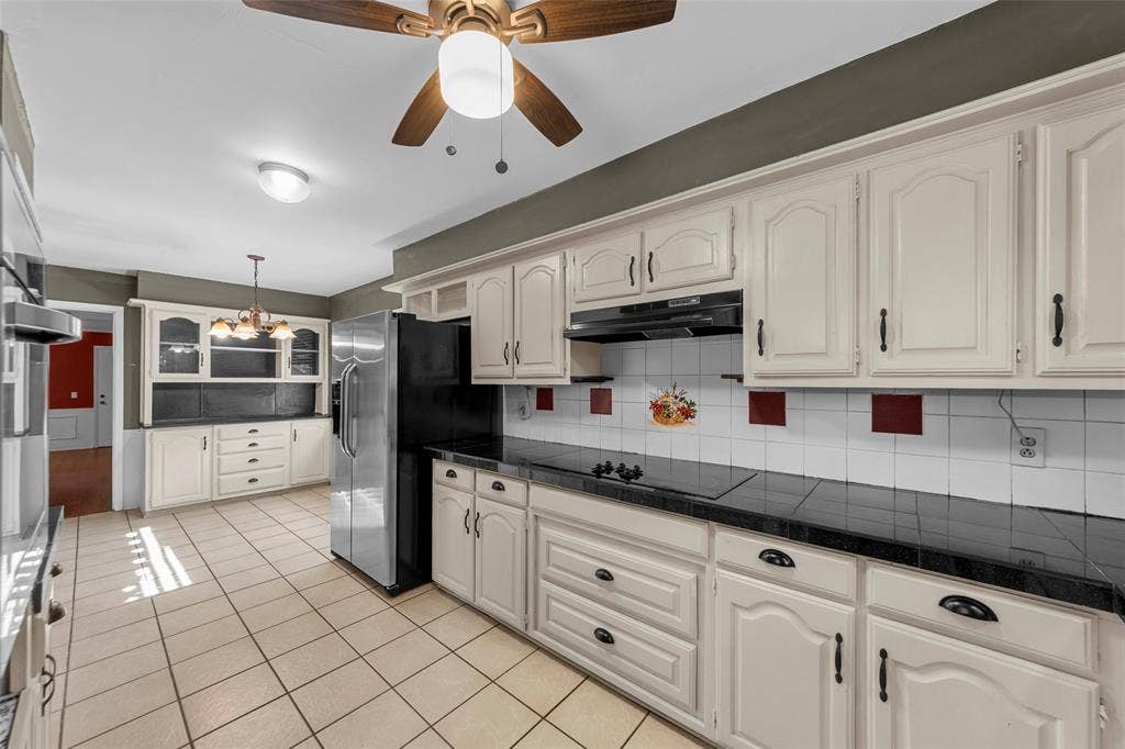 1116 Windsong Trail, Richardson, TX 75081 Kitchen with white cabinetry, black countertops, tile flooring, and a stainless steel refrigerator