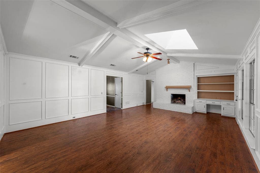 1116 Windsong Trail, Richardson, TX 75081 Spacious living area featuring wood-finish flooring, a vaulted ceiling with exposed beams, and a skylight
