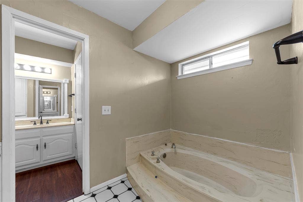 1116 Windsong Trail, Richardson, TX 75081 Built-in bathtub with a stone-finish surround, transom window, and black and white tile flooring