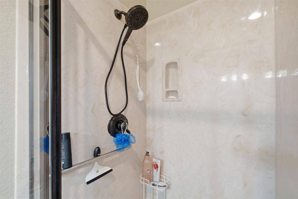 600 N Avalon Court, Granbury, TX 76048 Shower enclosure featuring matte black hardware, a multi-function shower head, integrated wall niche, and low-maintenance surround panels