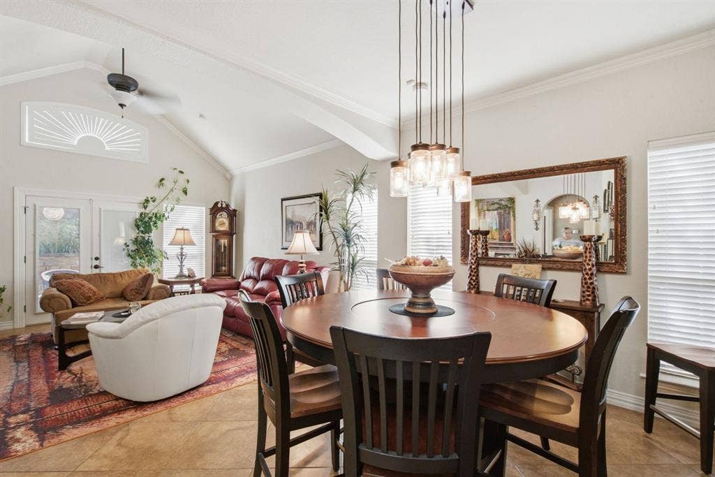 600 N Avalon Court, Granbury, TX 76048 Vaulted ceilings, expansive tile flooring, multi-light pendant chandelier, sunburst-style transom window, and ceiling fan.
