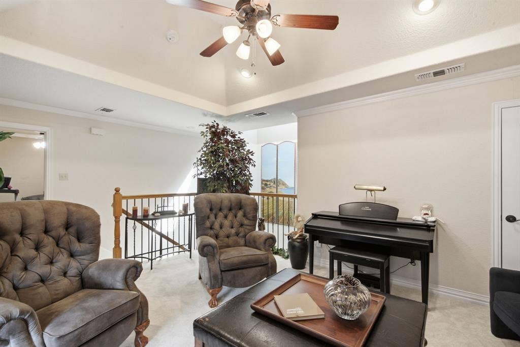 600 N Avalon Court, Granbury, TX 76048 Upstairs living area with tray ceiling featuring recessed lighting and a central ceiling fan with multi-light fixture, offset by a decorative metal baluster railing