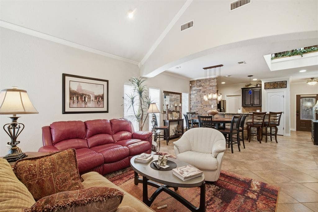 600 N Avalon Court, Granbury, TX 76048 Vaulted ceilings, stone-accented kitchen partition, tile flooring, built-in cabinetry, and multi-light pendant fixture