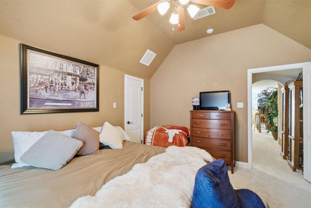 600 N Avalon Court, Granbury, TX 76048 Upstairs bedroom with vaulted ceiling featuring a ceiling fan with integrated lighting