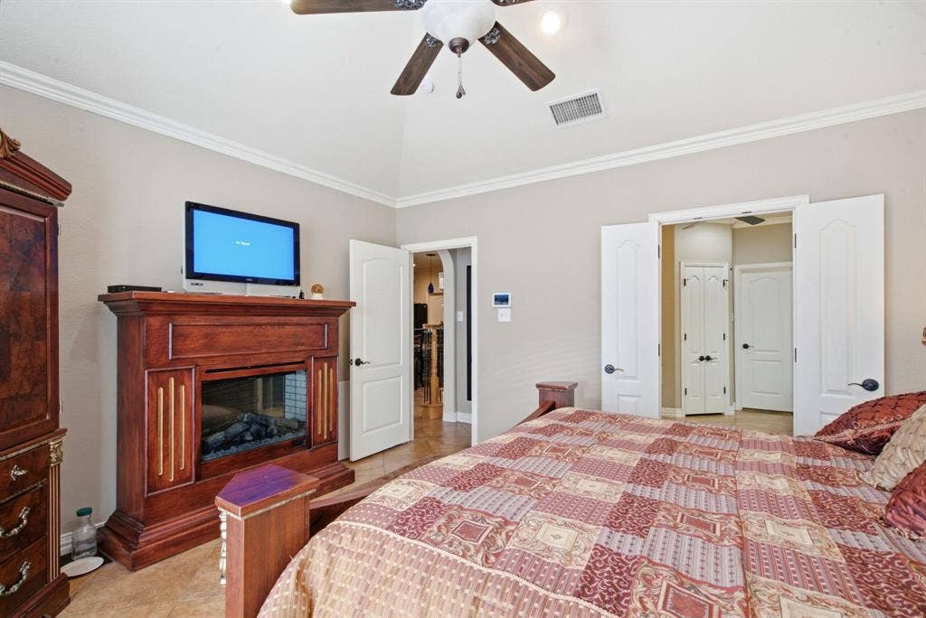 600 N Avalon Court, Granbury, TX 76048 Vaulted ceiling with crown molding, wood-finish mantel fireplace, ceramic tile flooring, and multi-panel interior doors