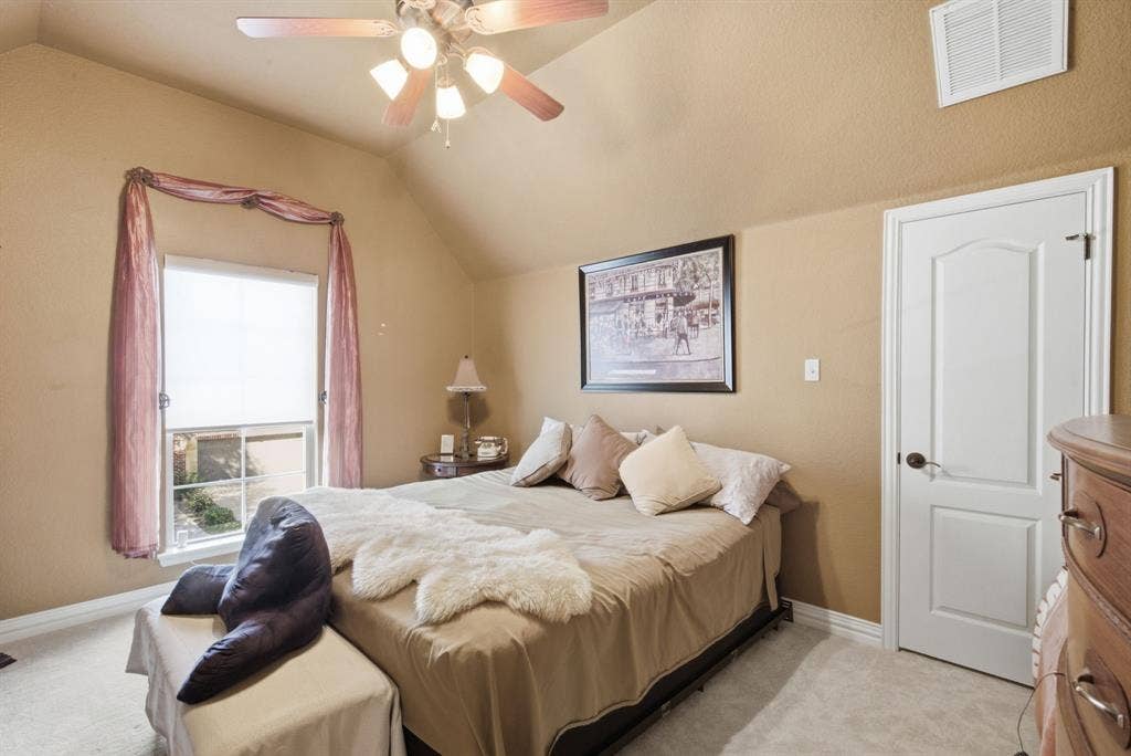 600 N Avalon Court, Granbury, TX 76048 Upstairs bedroom with vaulted ceilings, a multi-light ceiling fan with integrated lighting, a multi-pane window, and a paneled interior door with oil-rubbed bronze hardware
