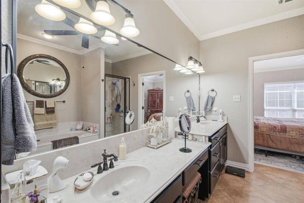 600 N Avalon Court, Granbury, TX 76048 Dual-sink vanity with light-toned solid surface countertops, dark cabinetry, oil-rubbed bronze fixtures, and a large-format frameless mirror