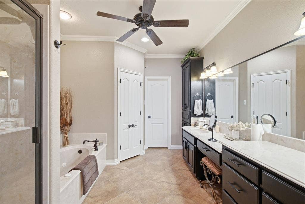 600 N Avalon Court, Granbury, TX 76048 Primary bathroom featuring a dual-sink vanity with dark cabinetry, light-toned countertops, a soaking tub with a wall-mounted faucet, a glass-enclosed shower, and tile flooring