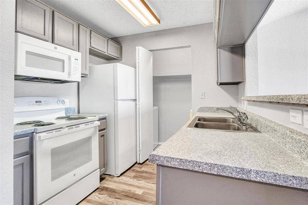 2500 E Park Boulevard, #P2, Plano, TX 75074 Modern kitchen featuring stainless steel appliances, including a gas range and microwave, paired with light cabinetry and speckled quartz countertops