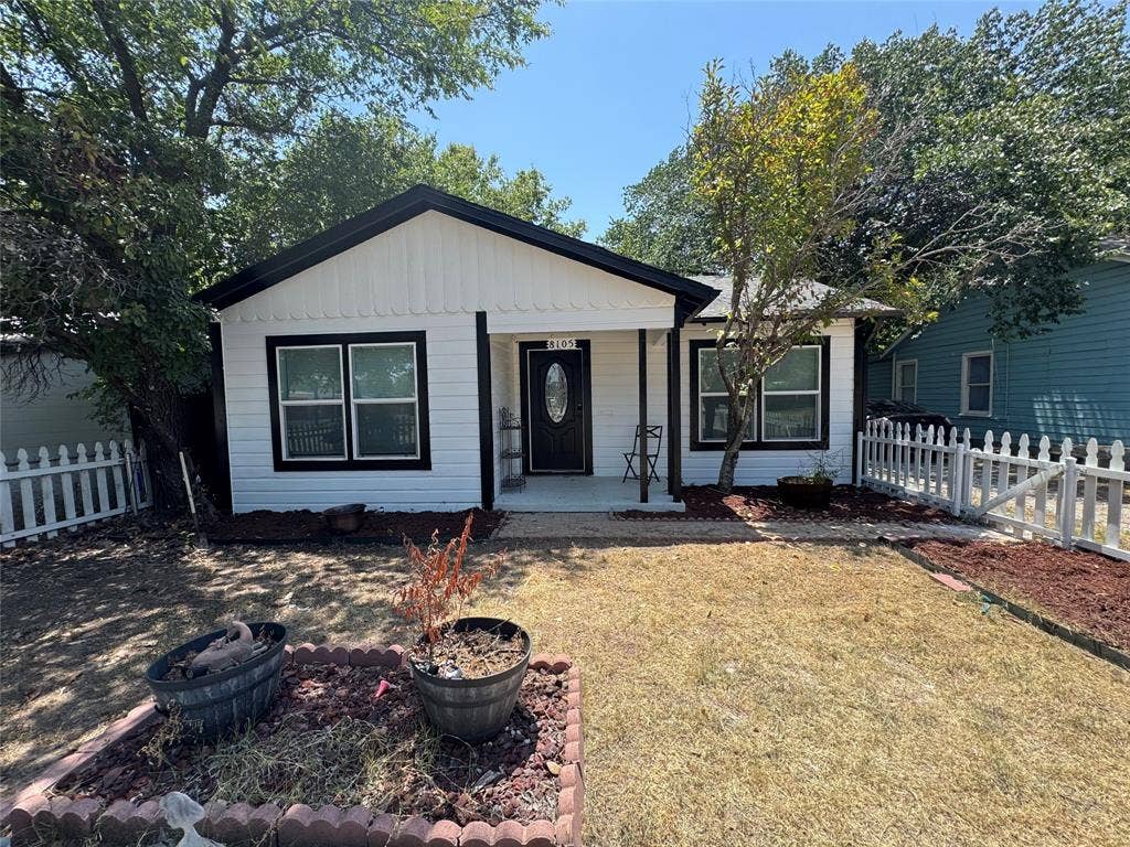8105 White Settlement Road, White Settlement, TX 76108 Charming cottage-style home featuring a gabled roof with black trim, white horizontal siding, and a covered front porch with black entry door