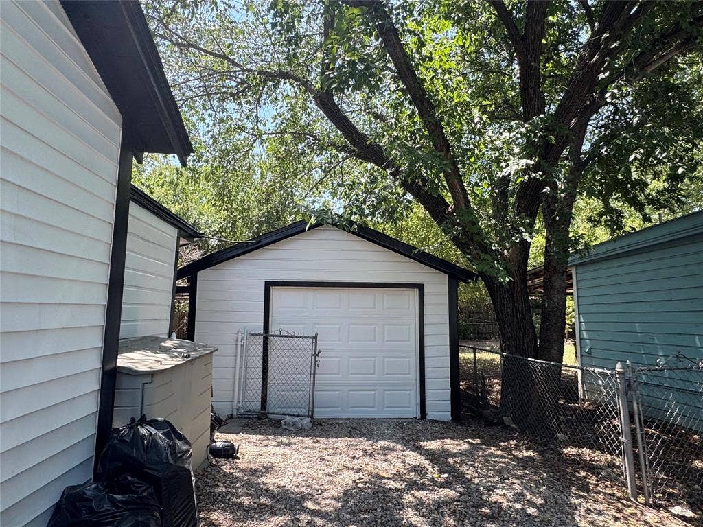 8105 White Settlement Road, White Settlement, TX 76108 Detached garage featuring a gabled roof design, white paneled exterior, and overhead sectional door