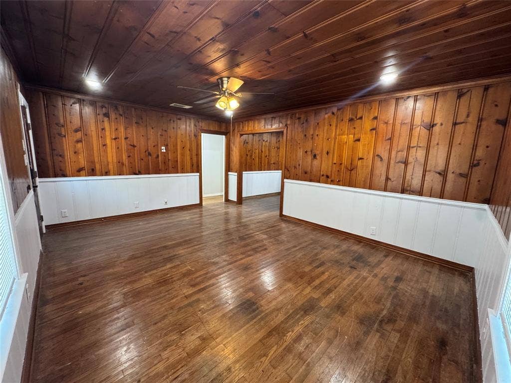 8105 White Settlement Road, White Settlement, TX 76108 Spacious interior featuring rich wood-finish flooring and wood paneling throughout, complemented by white wainscoting